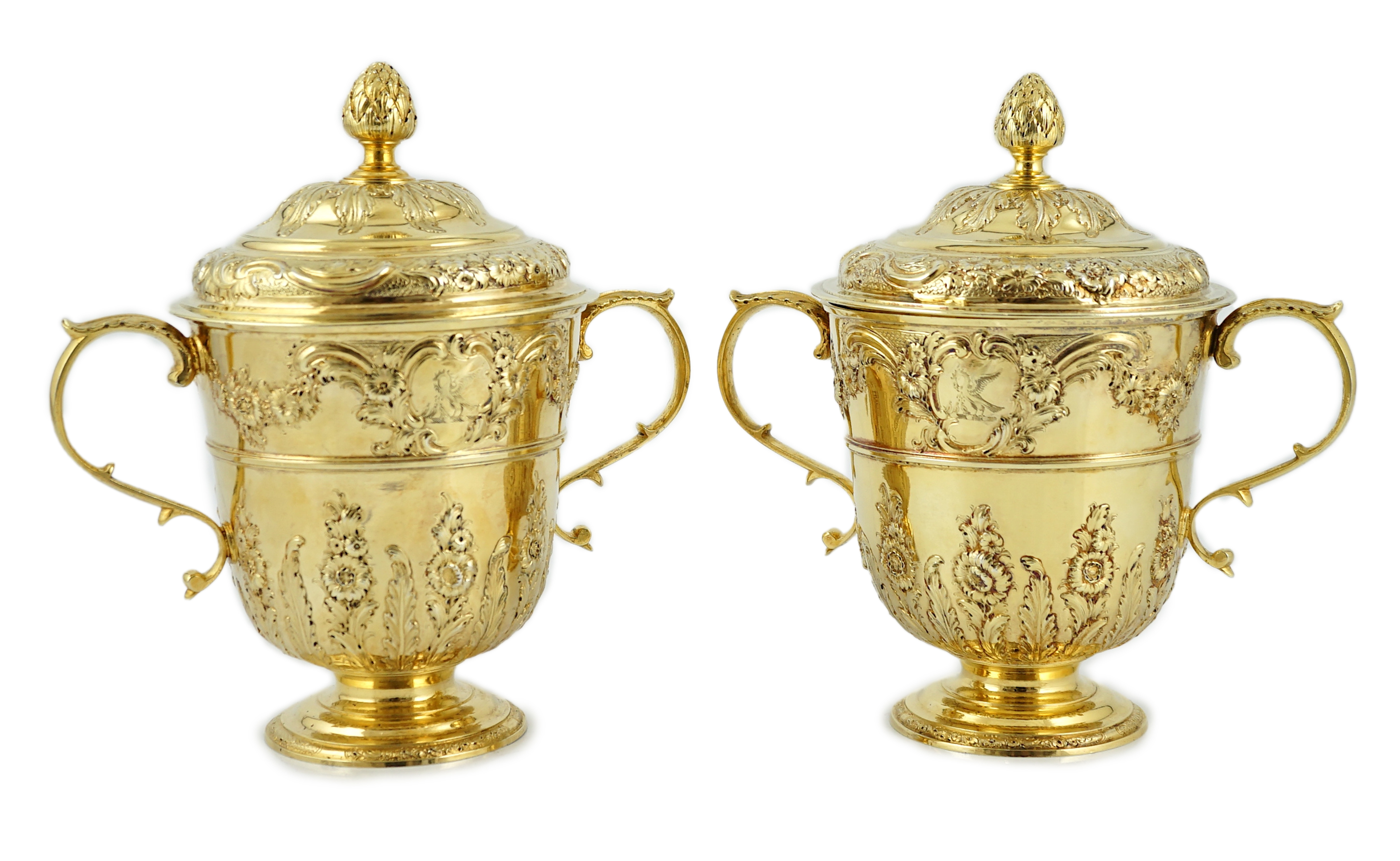 Benacre Hall, Suffolk. A good pair of George II embossed silver gilt two handled pedestal cups and covers, by Benjamin Gignac